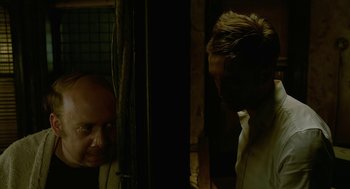 Movie still from “Cosmopolis” (2012), directed by David Cronenberg – A man standing next to another man in front of a window; Medium shot, Over the shoulder angle