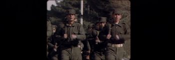 Movie still from “Flee” (2021), directed by Jonas Poher Rasmussen – A group of men in uniform marching down a street; Medium shot, Low angle