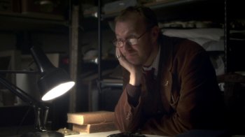 Movie still from “Crooked House” (2017), directed by Gilles Paquet-Brenner – A man sitting at a table in a room; Close Up shot, High angle