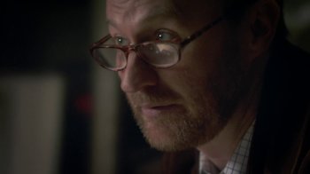 Movie still from “Crooked House” (2017), directed by Gilles Paquet-Brenner – A person wearing glasses; Close Up shot, Over the shoulder angle