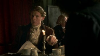 Movie still from “Crooked House” (2017), directed by Gilles Paquet-Brenner – A woman sitting at a dinner table with a candle; Medium shot, Over the shoulder angle