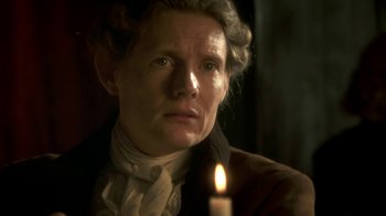 Movie still from “Crooked House” (2017), directed by Gilles Paquet-Brenner – An older woman is looking at the camera with a candle in the foreground; Close Up shot, Over the shoulder angle