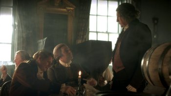 Movie still from “Crooked House” (2017), directed by Gilles Paquet-Brenner – A group of people sitting around a table with a candle; Medium shot, Over the shoulder angle