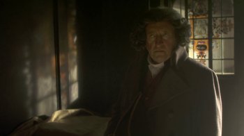 Movie still from “Crooked House” (2017), directed by Gilles Paquet-Brenner – A man in a brown coat and a white shirt; Close Up shot, Over the shoulder angle