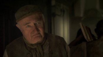 Movie still from “Crooked House” (2017), directed by Gilles Paquet-Brenner – An older man wearing a hat and a jacket; Close Up shot, Over the shoulder angle