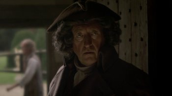 Movie still from “Crooked House” (2017), directed by Gilles Paquet-Brenner – An old man wearing a brown hat and a brown coat; Close Up shot, Over the shoulder angle