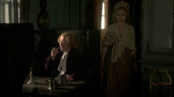 Movie still from “Crooked House” (2017), directed by Gilles Paquet-Brenner – A man and a woman sitting at a table in front of a window; Medium shot, Over the shoulder angle