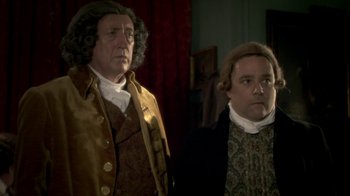 Movie still from “Crooked House” (2017), directed by Gilles Paquet-Brenner – A man and a woman dressed in period clothing; Medium shot, Over the shoulder angle