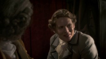 Movie still from “Crooked House” (2017), directed by Gilles Paquet-Brenner – A man in a suit is smiling for the camera; Close Up shot, Over the shoulder angle