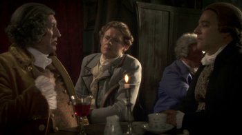 Movie still from “Crooked House” (2017), directed by Gilles Paquet-Brenner – Three people sitting at a table with a lit candle; Medium shot, Over the shoulder angle