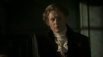 Movie still from “Crooked House” (2017), directed by Gilles Paquet-Brenner – A man wearing a suit and a white shirt; Close Up shot, Over the shoulder angle