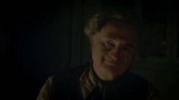 Movie still from “Crooked House” (2017), directed by Gilles Paquet-Brenner – An older man smiling for the camera in the dark; Close Up shot, Low angle