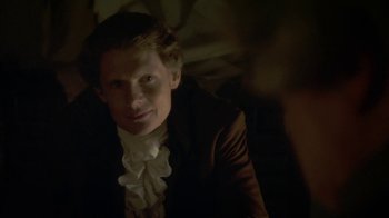 Movie still from “Crooked House” (2017), directed by Gilles Paquet-Brenner – A man in a suit and a white shirt is smiling for the camera; Close Up shot, Over the shoulder angle