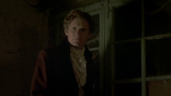 Movie still from “Crooked House” (2017), directed by Gilles Paquet-Brenner – A man in a black suit standing next to a door; Close Up shot, Low angle