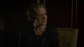 Movie still from “Crooked House” (2017), directed by Gilles Paquet-Brenner – A woman in a black dress sitting on a couch; Close Up shot, Over the shoulder angle