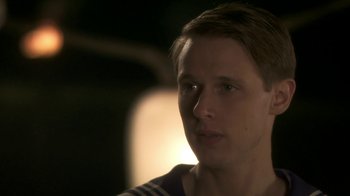 Movie still from “Crooked House” (2017), directed by Gilles Paquet-Brenner – A young man is looking into the camera; Close Up shot, Over the shoulder angle