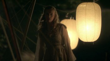 Movie still from “Crooked House” (2017), directed by Gilles Paquet-Brenner – A woman standing in the dark near a lantern; Medium shot, Over the shoulder angle