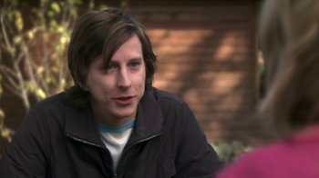 Movie still from “Crooked House” (2017), directed by Gilles Paquet-Brenner – A man with long brown hair wearing a black jacket; Close Up shot, Over the shoulder angle