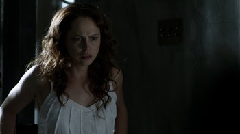 Movie still from “Curse of Chucky” (2013), directed by Don Mancini – A woman in a white dress is standing in a dark room; Close Up shot, Over the shoulder angle
