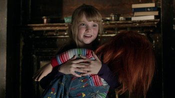 Movie still from “Curse of Chucky” (2013), directed by Don Mancini – A little girl is holding a doll in her arms; Medium shot, Over the shoulder angle