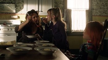 Movie still from “Curse of Chucky” (2013), directed by Don Mancini – A woman and two children are sitting at a dinner table; Medium shot, Over the shoulder angle