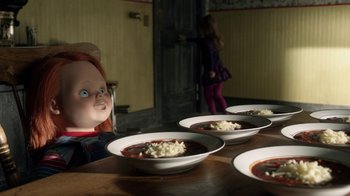 Movie still from “Curse of Chucky” (2013), directed by Don Mancini – Three bowls of chili and a doll sitting on a table; Medium shot, High angle