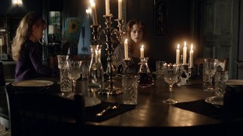 Movie still from “Curse of Chucky” (2013), directed by Don Mancini – A woman sitting in front of some candles on a dining room table; Wide shot, Over the shoulder angle