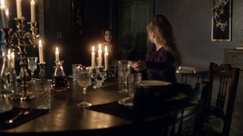 Movie still from “Curse of Chucky” (2013), directed by Don Mancini – Two people sitting at a table with candles in a dark room; Medium shot, Over the shoulder angle