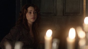 Movie still from “Curse of Chucky” (2013), directed by Don Mancini – A woman sitting in front of a lit candle in a dark room; Close Up shot, Over the shoulder angle