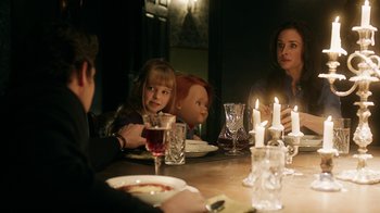 Movie still from “Curse of Chucky” (2013), directed by Don Mancini – A group of people sitting at a table with candles; Medium shot, Over the shoulder angle