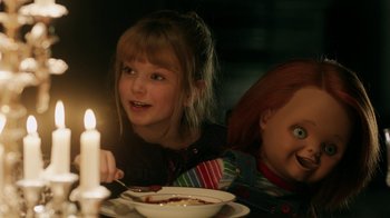 Movie still from “Curse of Chucky” (2013), directed by Don Mancini – Two children sitting at a dinner table with a candle; Medium shot, Over the shoulder angle