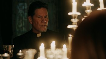Movie still from “Curse of Chucky” (2013), directed by Don Mancini – A man in a priest's outfit looking into a mirror; Close Up shot, Over the shoulder angle
