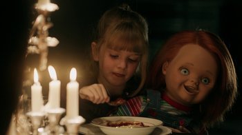 Movie still from “Curse of Chucky” (2013), directed by Don Mancini – A girl and a doll eating a bowl of soup; Medium shot, Over the shoulder angle