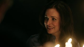 Movie still from “Curse of Chucky” (2013), directed by Don Mancini – A woman smiles while holding a candle in her hand; Close Up shot, Over the shoulder angle