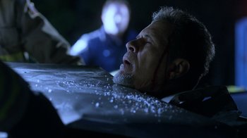 Movie still from “Curse of Chucky” (2013), directed by Don Mancini – A man is laying on the ground with a knife in his mouth; Close Up shot, Low angle