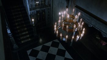 Movie still from “Curse of Chucky” (2013), directed by Don Mancini – A chandelier in the middle of a room with a checkerboard floor; Extreme Wide shot, Overhead angle
