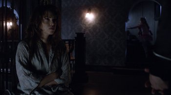 Movie still from “Curse of Chucky” (2013), directed by Don Mancini – A woman sitting on a chair in a dark room; Medium shot, Over the shoulder angle