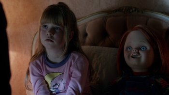 Movie still from “Curse of Chucky” (2013), directed by Don Mancini – A little girl sitting next to a doll on a bed; Close Up shot, Over the shoulder angle