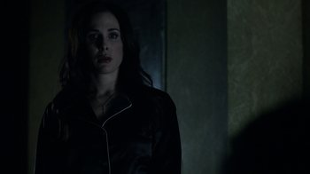 Movie still from “Curse of Chucky” (2013), directed by Don Mancini – A woman standing in a dark room looking at the camera; Close Up shot, Over the shoulder angle