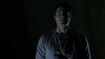 Movie still from “Curse of Chucky” (2013), directed by Don Mancini – A man with blood on his face is standing in the dark; Close Up shot, Low angle