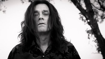 Movie still from “Curse of Chucky” (2013), directed by Don Mancini – A black and white photo of a man with long hair; Close Up shot, Low angle