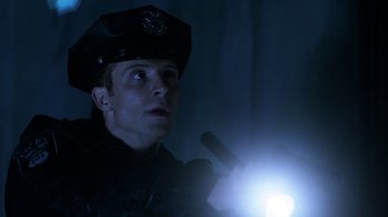 Movie still from “Curse of Chucky” (2013), directed by Don Mancini – A man in a police uniform looking up at a light; Close Up shot, Low angle