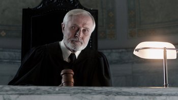 Movie still from “Curse of Chucky” (2013), directed by Don Mancini – An old man in a court robe and a gavel in front of a mirror; Close Up shot, Low angle