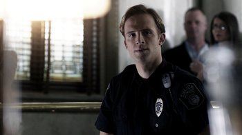 Movie still from “Curse of Chucky” (2013), directed by Don Mancini – A man in a police uniform is looking at the camera; Close Up shot, Over the shoulder angle