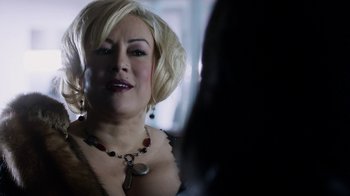 Movie still from “Curse of Chucky” (2013), directed by Don Mancini – A woman with blonde hair wearing a necklace and earrings; Close Up shot, Over the shoulder angle