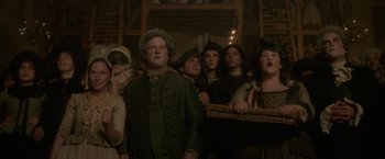 Movie still from “Cyrano” (2021), directed by Joe Wright – A group of people standing in a room; Medium shot, Low angle