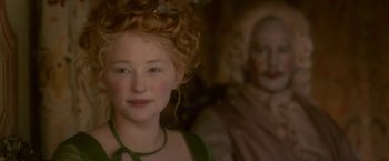 Movie still from “Cyrano” (2021), directed by Joe Wright – A woman with a red curly hair and a green dress; Close Up shot, Over the shoulder angle