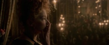 Movie still from “Cyrano” (2021), directed by Joe Wright – A woman with curly red hair holding her hands to her face; Close Up shot, Over the shoulder angle