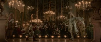Movie still from “Cyrano” (2021), directed by Joe Wright – A group of people sitting in front of candles; Wide shot, Low angle