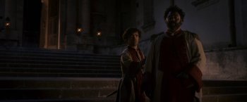 Movie still from “Cyrano” (2021), directed by Joe Wright – A man standing next to another man in front of a building; Medium shot, Low angle